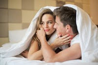 pareja hablando de sexualidad debajo de las sabanas